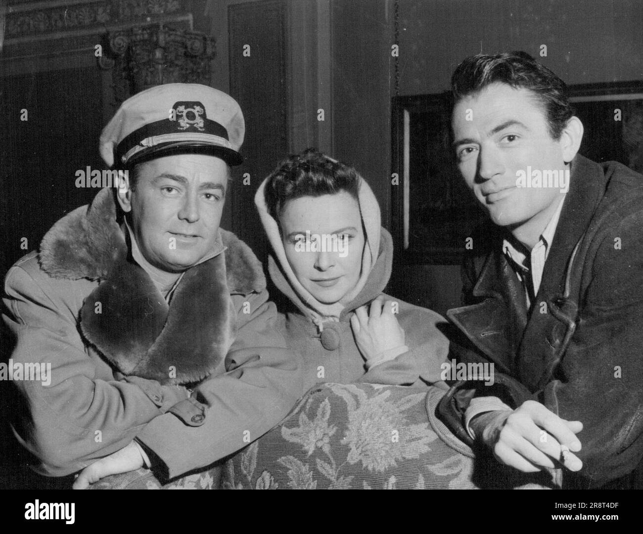 uYanks Who Are Playing Away -- Handsome and glamorous American trio in an 'away from home' chat are all currently filming at Pinewood, England. Gregory Peck, right, paid a visit to his old friend Alan Ladd on the 'Hell Bellow Zero' set and met Ladd's new leading lady, actress Joan ('Little Hut') Tetzel. 'Hell Below Zero' is a Warwick films Technicolor production for Columbia release. May 11, 1953. (Photo by Reuterphoto). Stock Photo