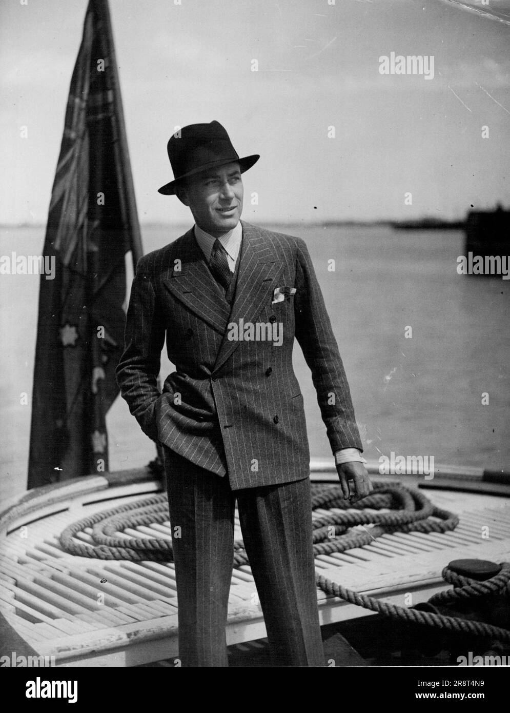 Dancing Teacher Returning Home : Mr. Carl Thomas, a Sydney dancing teacher, who has been on a seven months tour abroad, photographed in the launch which brought passengers ashore from the Port Fremantle. The vessel is loading explosives at Altona. March 30, 1936. Stock Photo