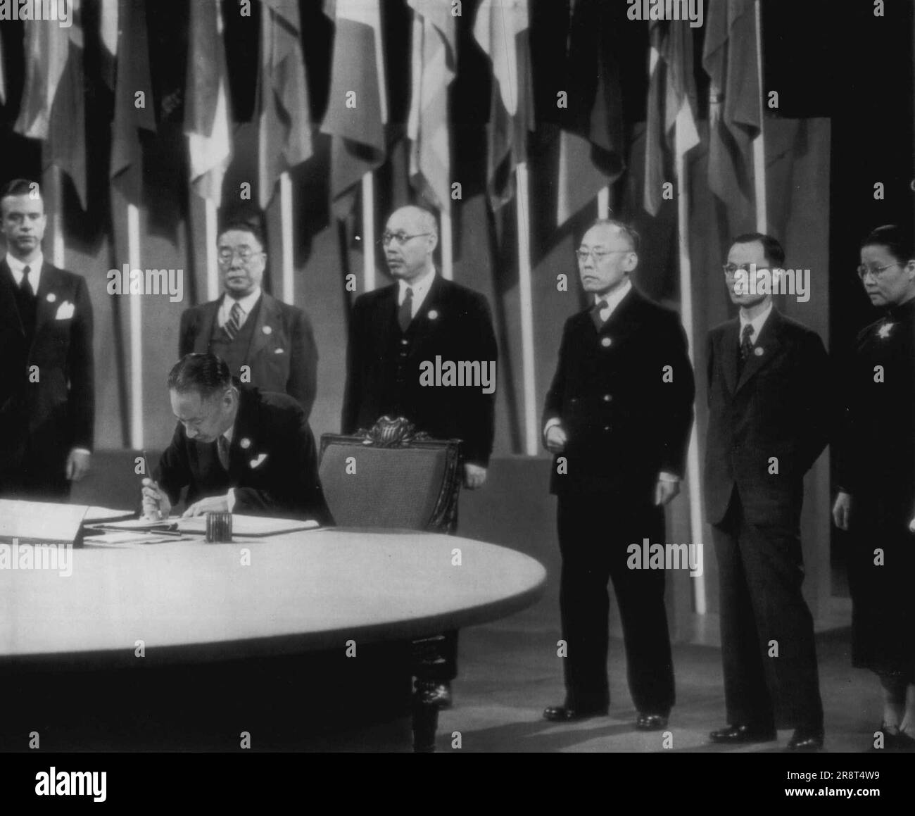 China First to Sign Chapter -- V.K. Wellington Koo, Chinese ambassador to the court of St. James, (Seated) is first to sign the United Nations security chapter, Standing behind, (L-R) are: Parker Hart, U.S. state department Hu Lin, Tune Pi-wu, Chun-Mai Carson change, Li Hwang, and Miss Wu-fang, members of the Chinese delegations. June 26, 1945. (Photo by AP Wirephoto). Stock Photo