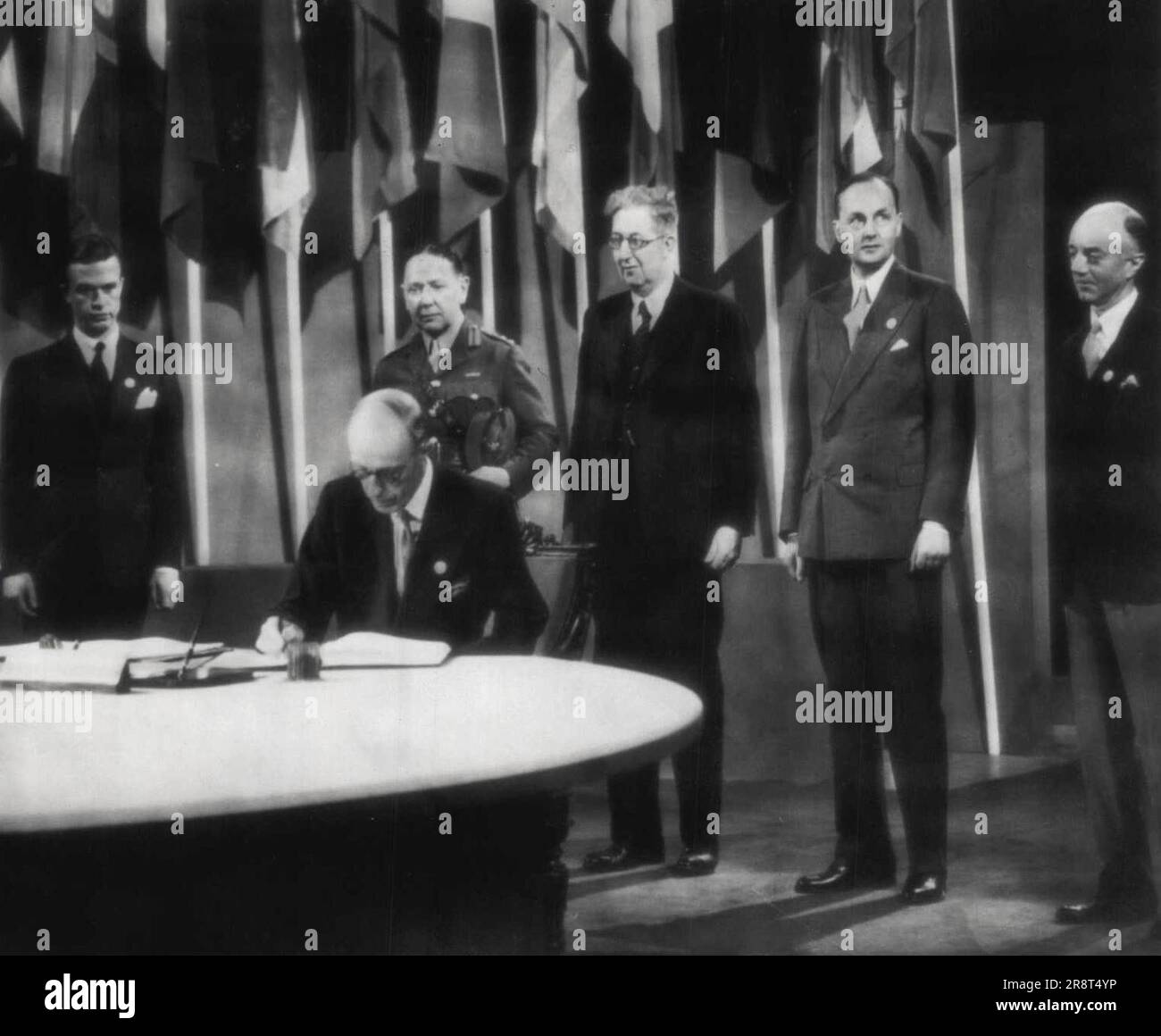 Halifax Signs For Britain -- The Earl of Halifax (seated), British ambassador to the U.S., signs the United Nations Security chapter here today as other members of the delegation look on Standing (L-R) Parker Hart, U.S. state department Col. D.Capel Dunn, C.K. Webster, H.M.G. Jebb, N.M. Buler. (Photo by AP Wirephoto). July 23, 1945. (Photo by AP Wirephoto). Stock Photo