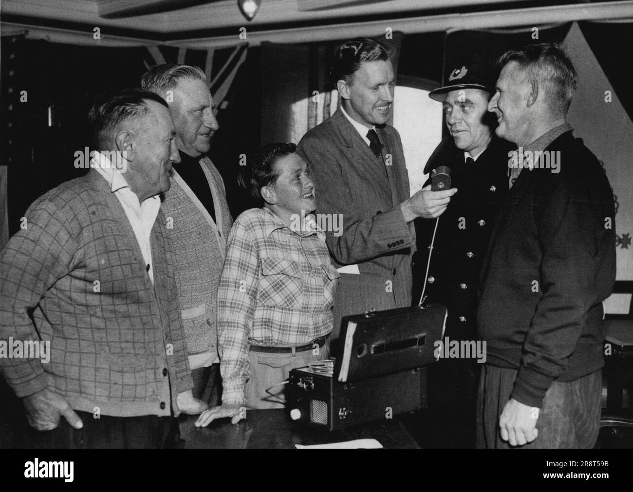 Fisherman who drifted out to sea from Botany Bay on Wednesday morning were rescued by the Dutch shop Tjibadak. Here they are being interviewed by 5DN/radio announcer Ken Chinner. Left to right - George Smith, Ernest Foster, Ray Hartley, Ken Chinner (announcer), Captain C. de Wolff, captain of the ship which rescued the men, and Frank Munsie. September 17, 1953. Stock Photo