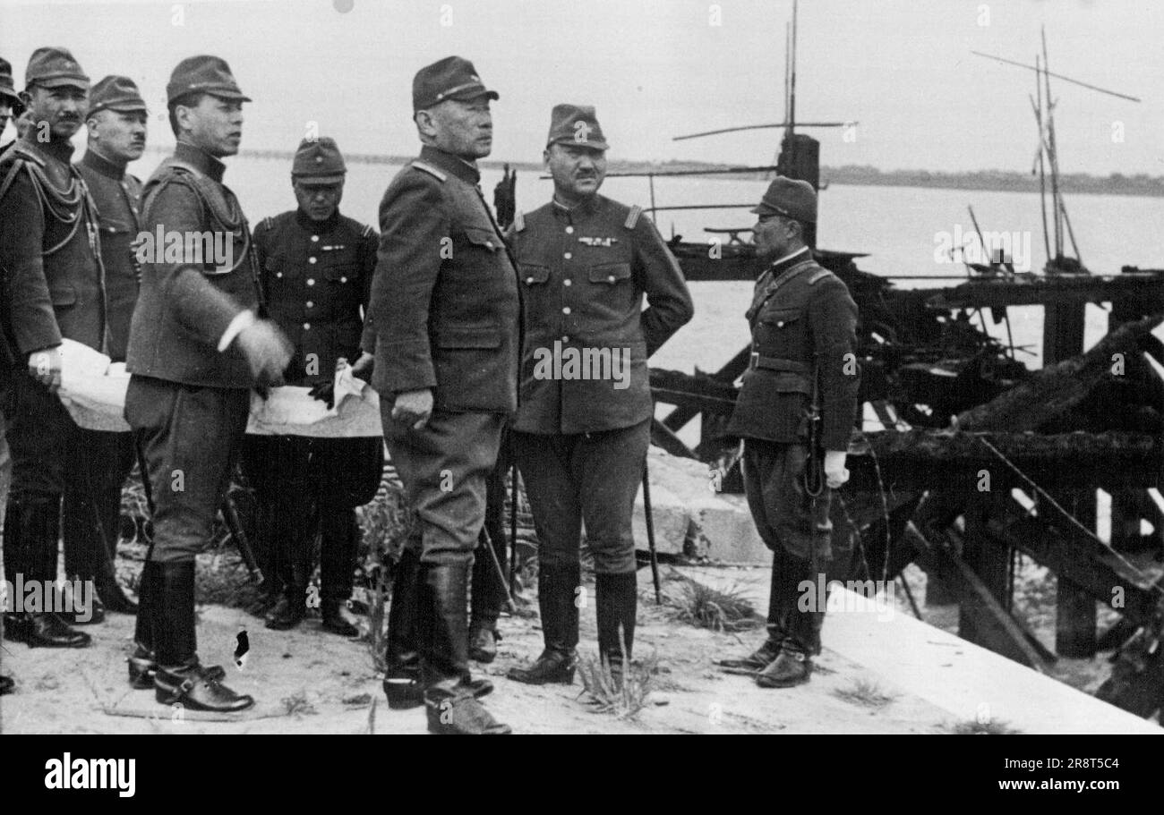 General Gen. Sugiyama, Japanese Minister of War, recently paid a flying visit to China inspecting conditions in North China and in Shanghai. General Sugiyama (3rd from right) is seen at Woosung, a few miles from Shanghai, looking over the ruined wharf where the first Japanese landing was effected. May 9, 1938. (Photo by Keystone). Stock Photo