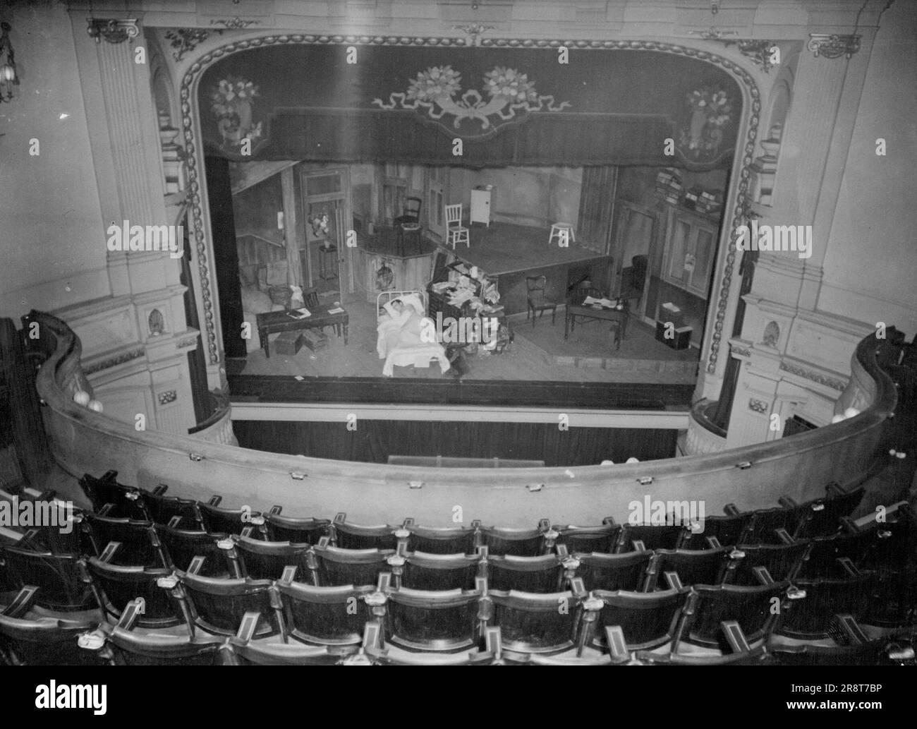 The man whose address is 'c.o. Joe Tomelty's Bed' settles down to his dreams on the stage of the empty silent, Ambassador's theater, London. Markey Robinson, of Belfast, came to London last week. First call he made was on some actor friends of his. 'Where can i sleep tonight?' he said. The only bed they could offer was one used in their play. Markey's pal, actor Joe Tomelty, 'dies' in it nightly. Then, when the audience has gone home, Markey turns in. July 18, 1951. (Photo by Daily Mirror) Stock Photo