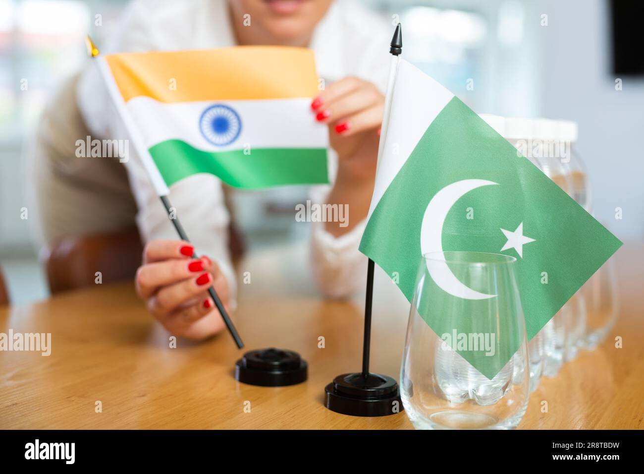 Young woman putting flags of India and Pakistan on table in office Stock Photo