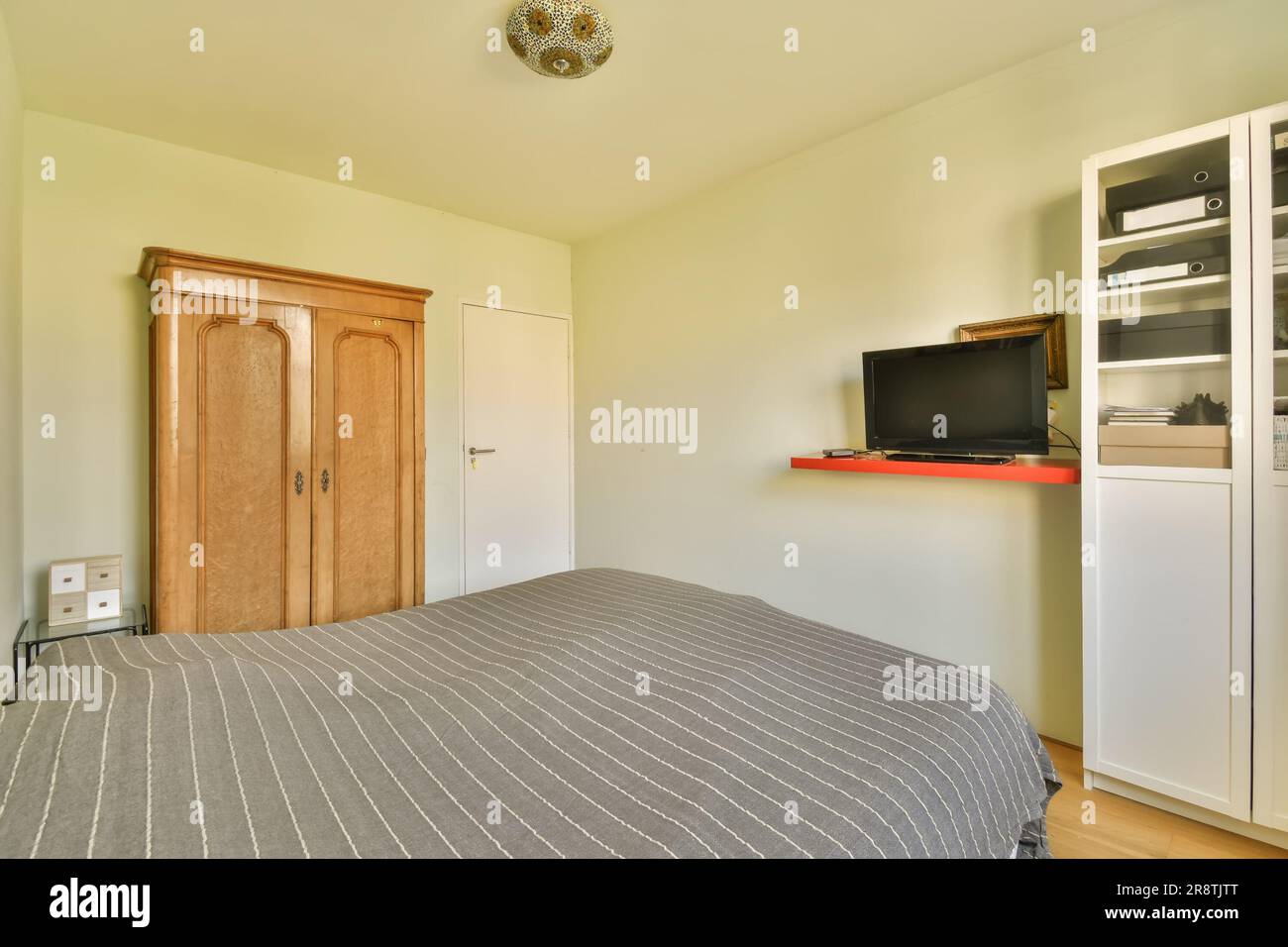 a bedroom with a bed, television and microwave on the wall in front of