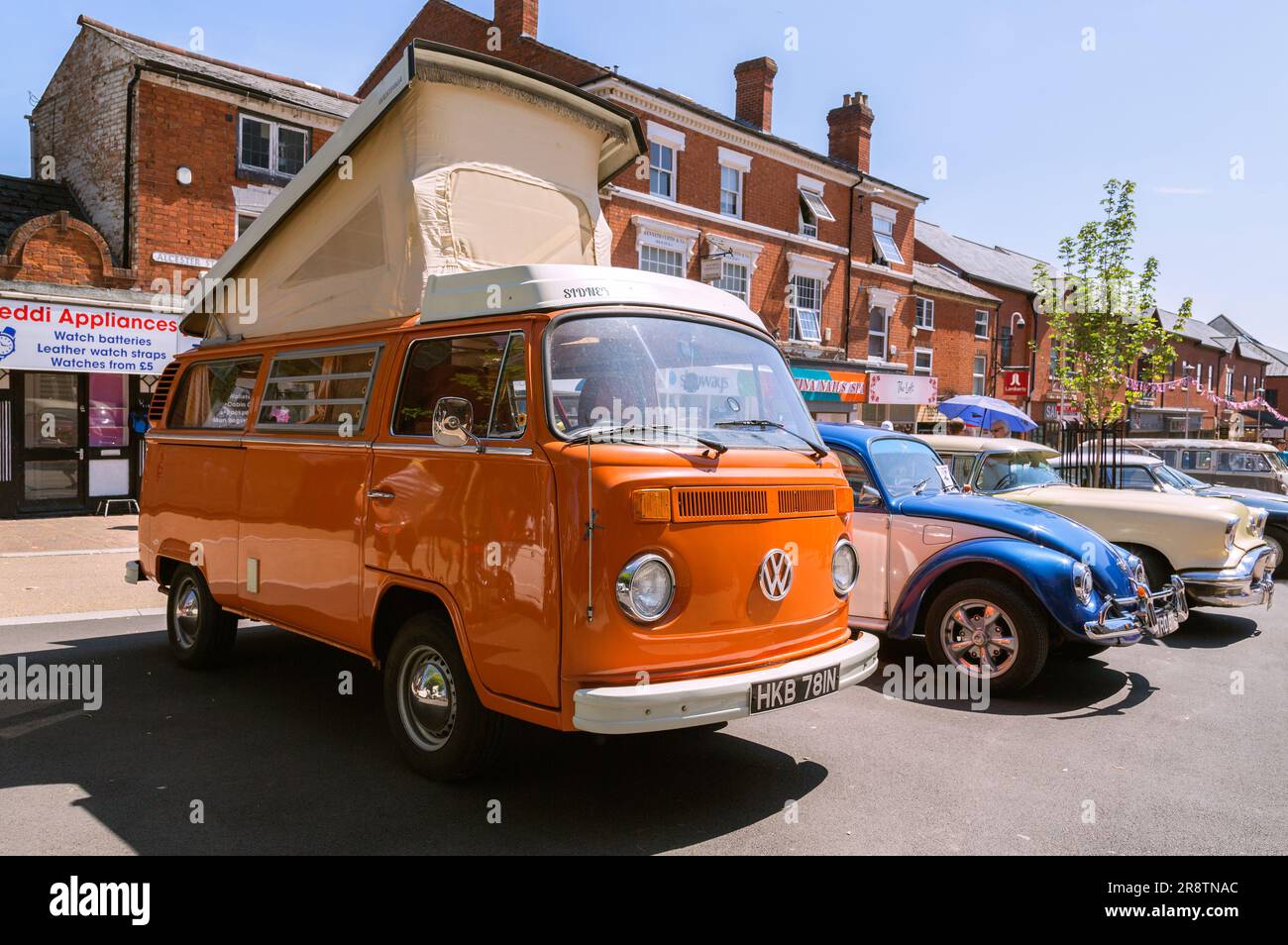 An orange 1970s Volkswagen camper van with its elevating roof raised up. VW camper van at classic and vintage car show. Stock Photo