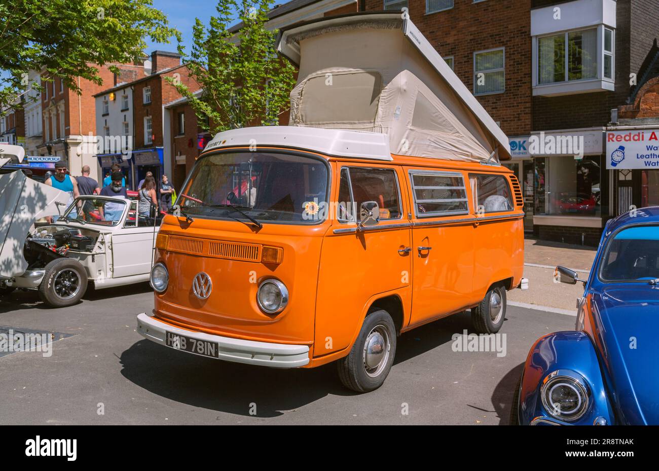 An orange 1970s Volkswagen camper van with its elevating roof raised up. VW camper van at classic and vintage car show. Stock Photo