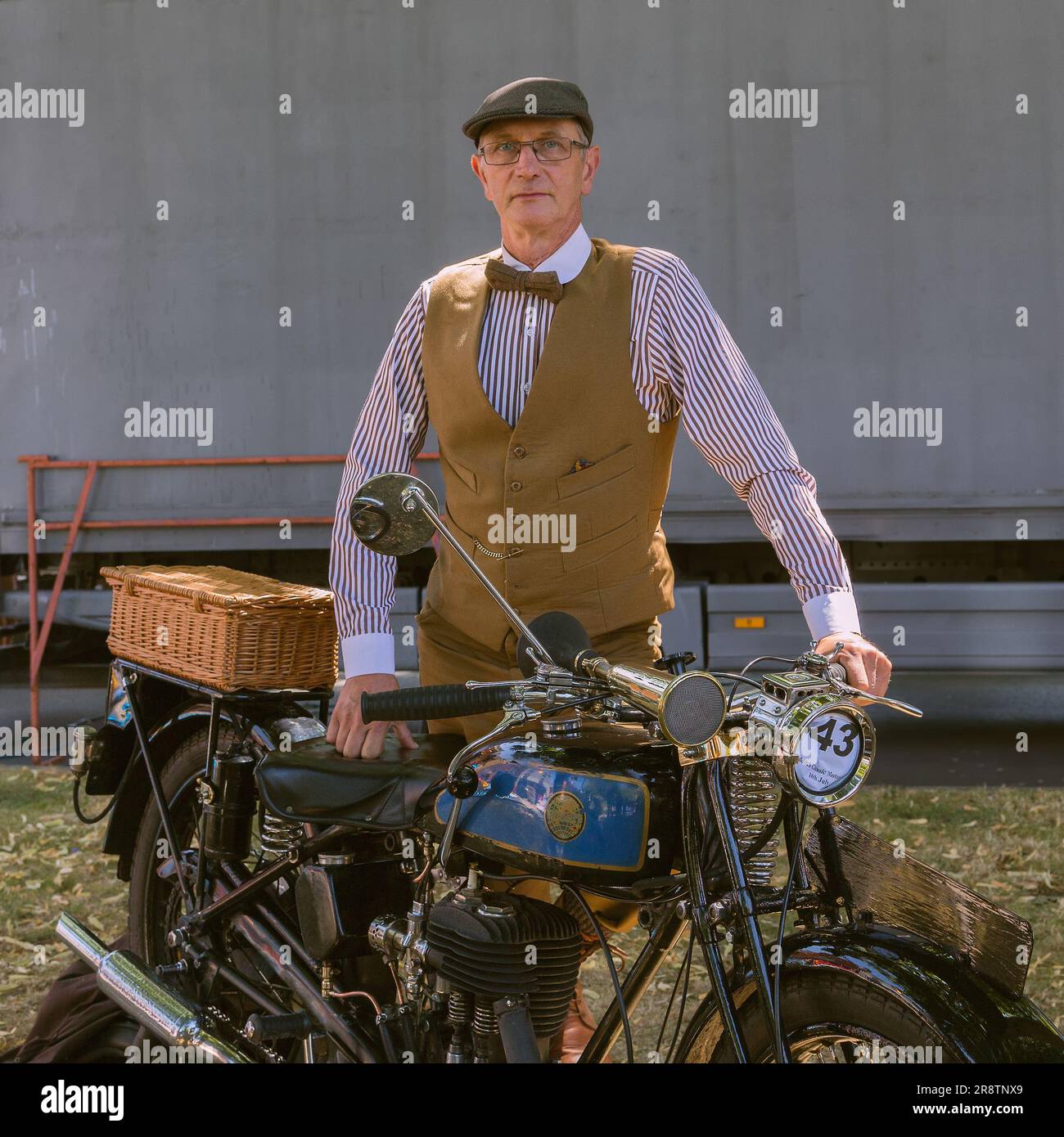A portrait of the proud owner of a Triumph Model NSD motorcycle standing next to his motorbike while dressed in period costume. Vintage motorcycle. Stock Photo