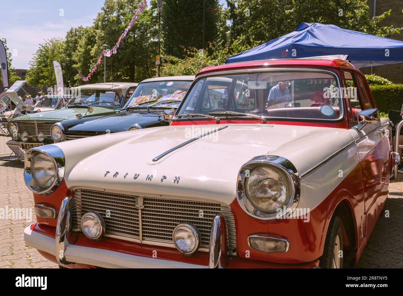 A Triumph Herald 12/50 is first in line at a Classic and Vintage car show. A row of vintage and classic cars gleaming in the sunshine. Stock Photo