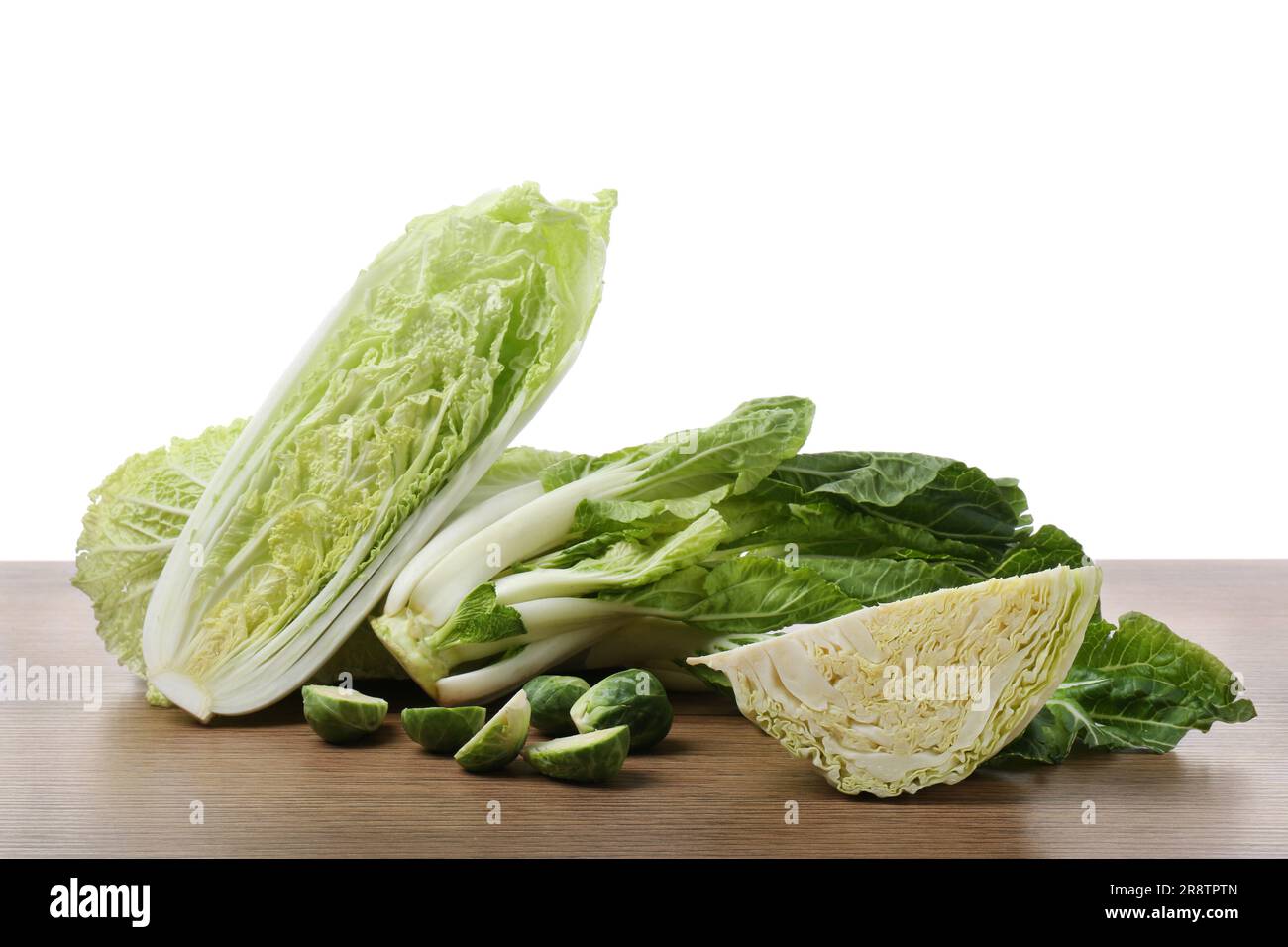 Different types of cut cabbage on wooden table against white background ...