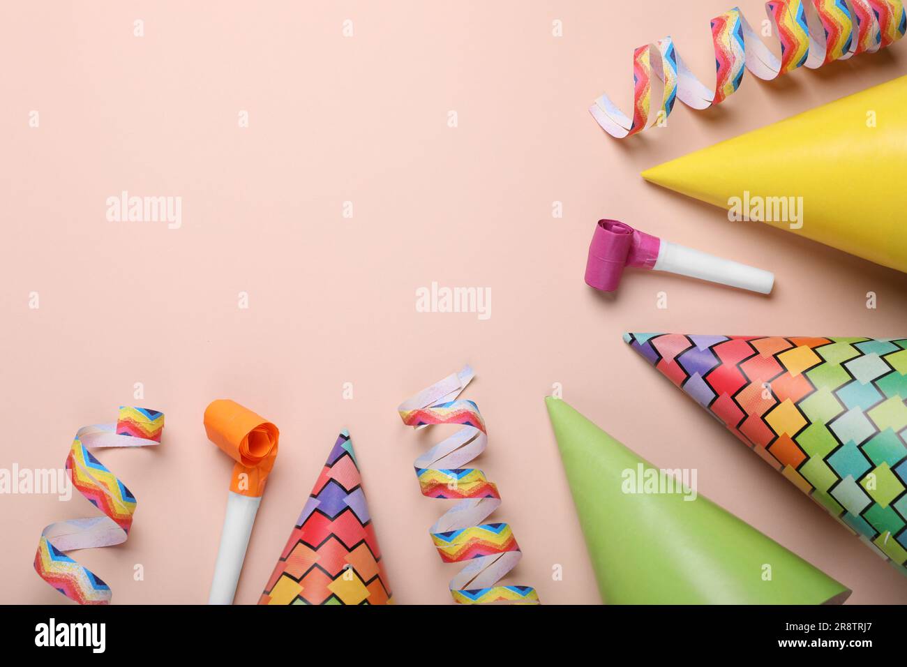 Flat lay composition with party hats and blowers on pale pink ...