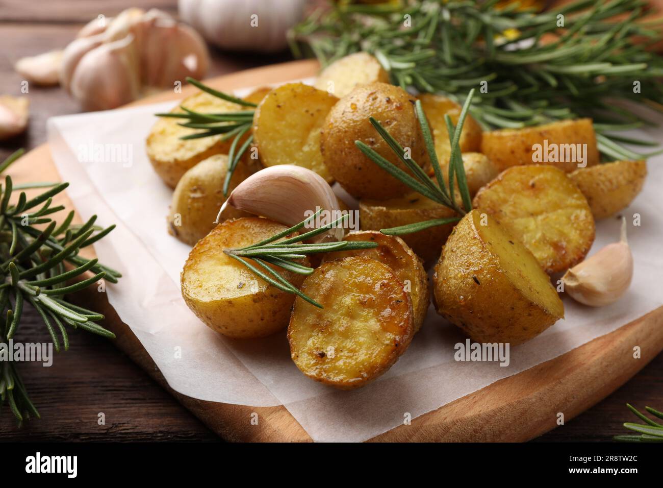 Delicious baked potatoes with rosemary and garlic on parchment paper
