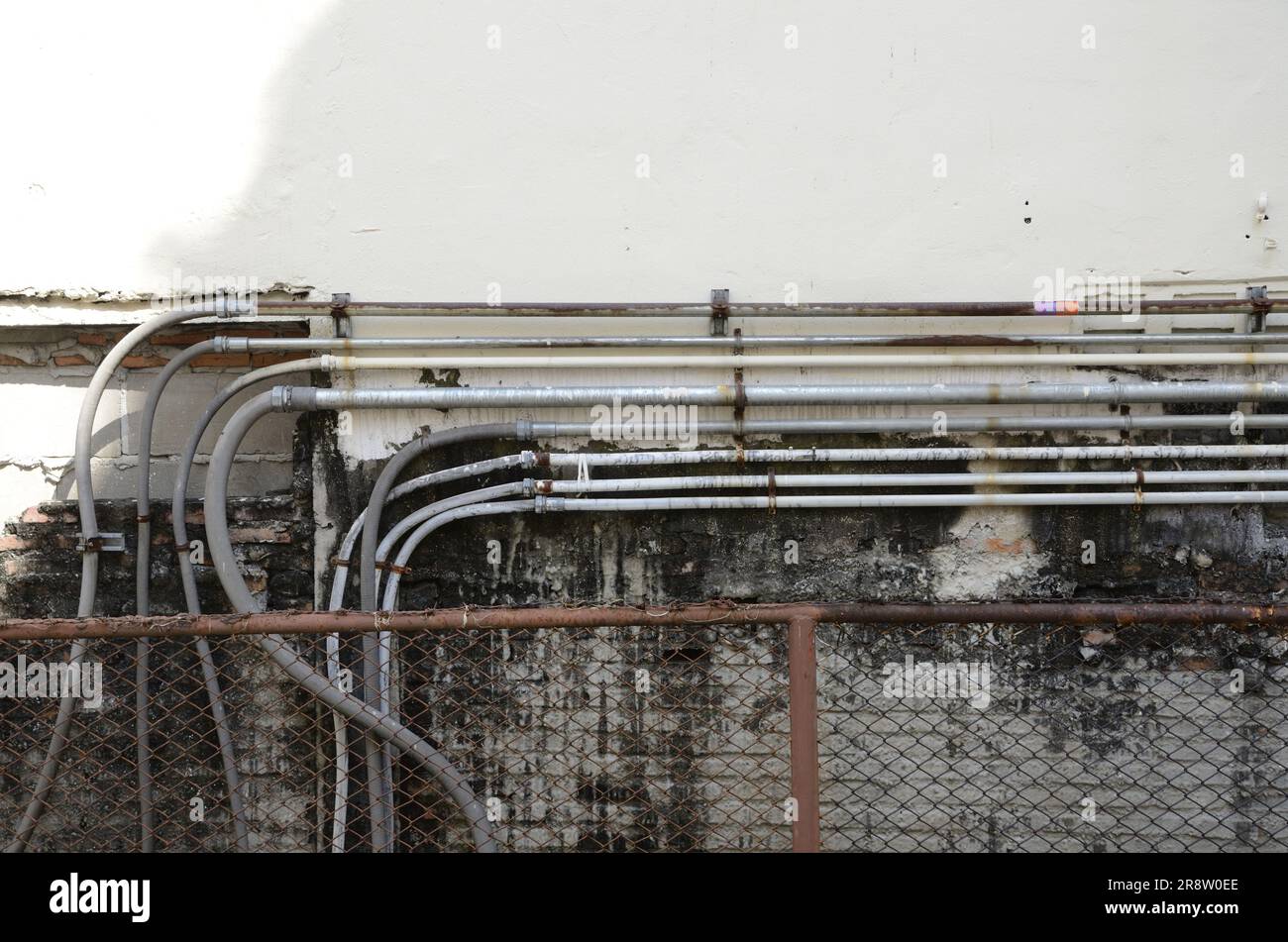 A closeup view of various electrical conduits mounted to a white wall