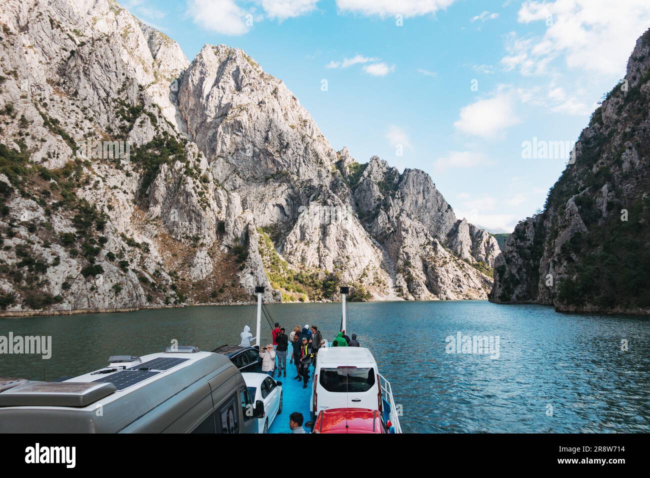 the Komani Lake Ferry navigates a rocky gorge with a payload of people and vehicles, on Lake Koman, Albania Stock Photo