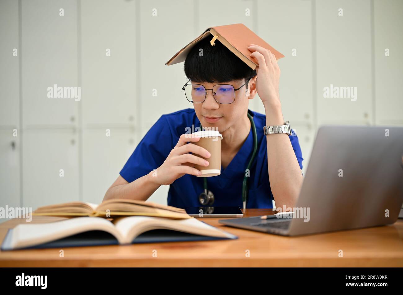 A smart and handsome young Asian male medical student is sipping coffee ...