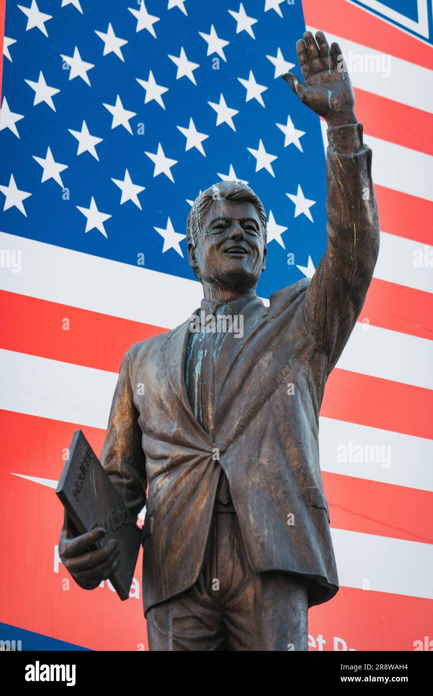 a statue of U.S. President Bill Clinton erected in 2009 on a plinth in front of an American flag billboard in Pristina, Kosovo Stock Photo