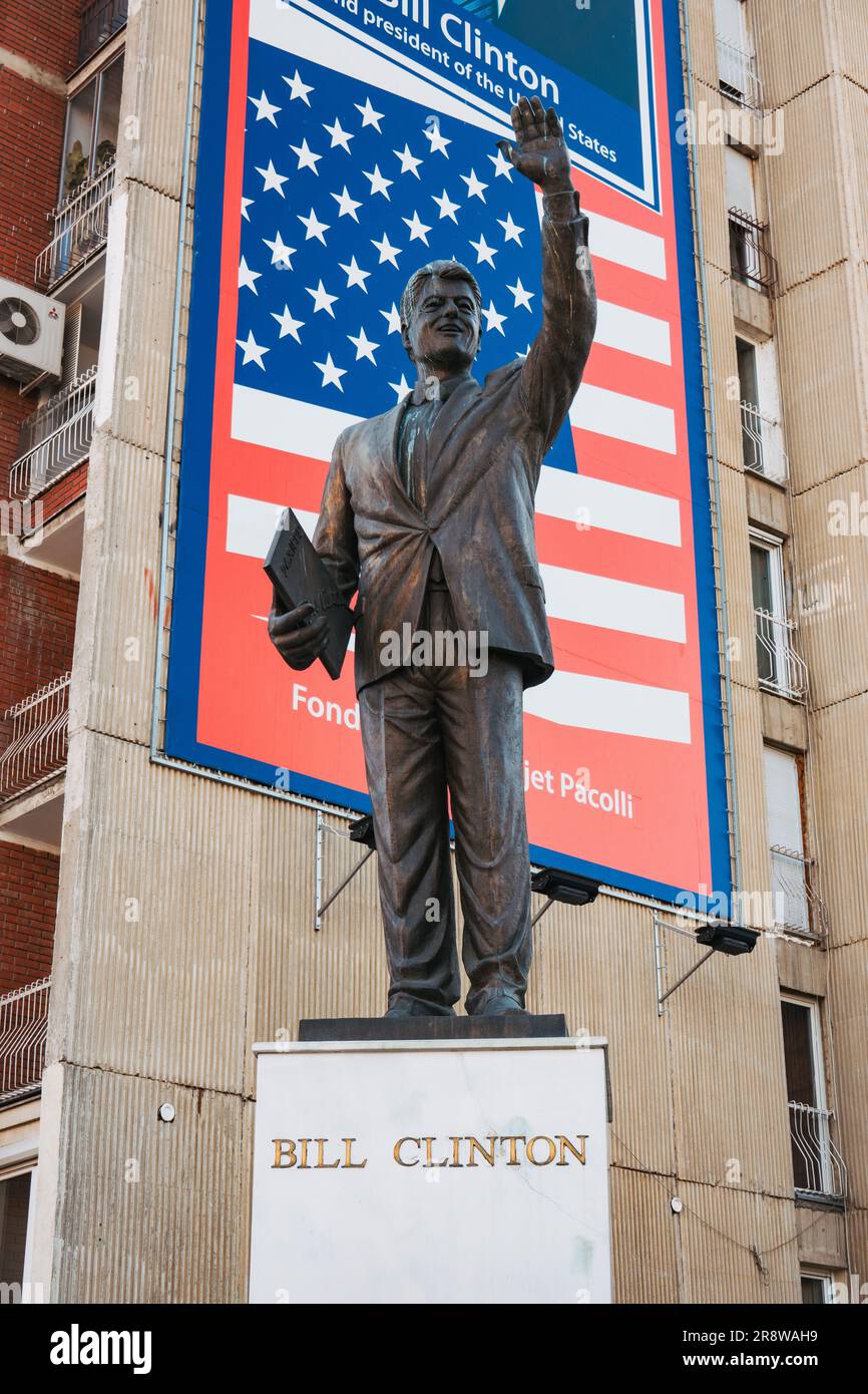 a statue of U.S. President Bill Clinton erected in 2009 on a plinth in front of an American flag billboard in Pristina, Kosovo Stock Photo