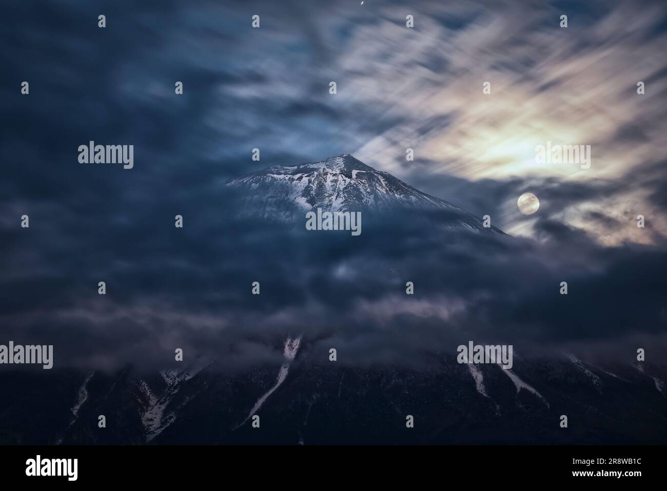 Full moon appearing from?the break in the clouds and Mt.Fuji Stock