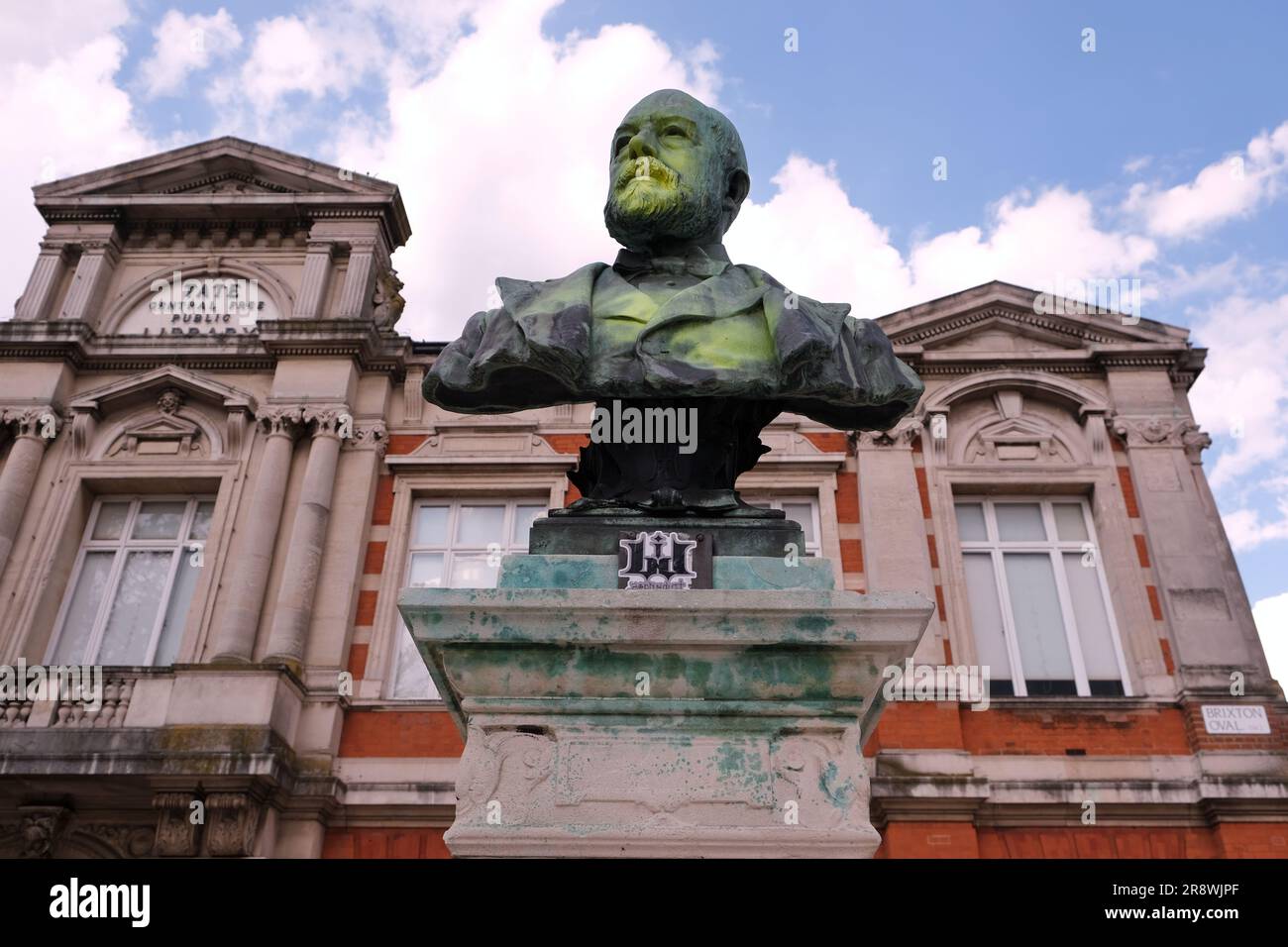 Brixton, UK. A bronze bust of Thomas Tate in Windrush Square is defaced with yellow paint, due to his indirect connection to the slave trade. Stock Photo