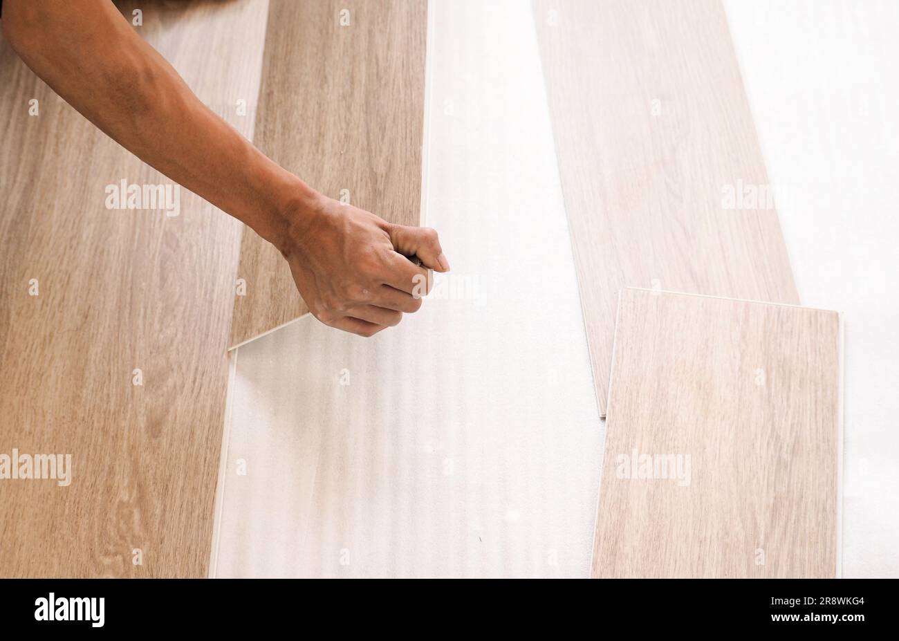 A technician is cutting luxury vinyl floor tiles with a cutter to lay