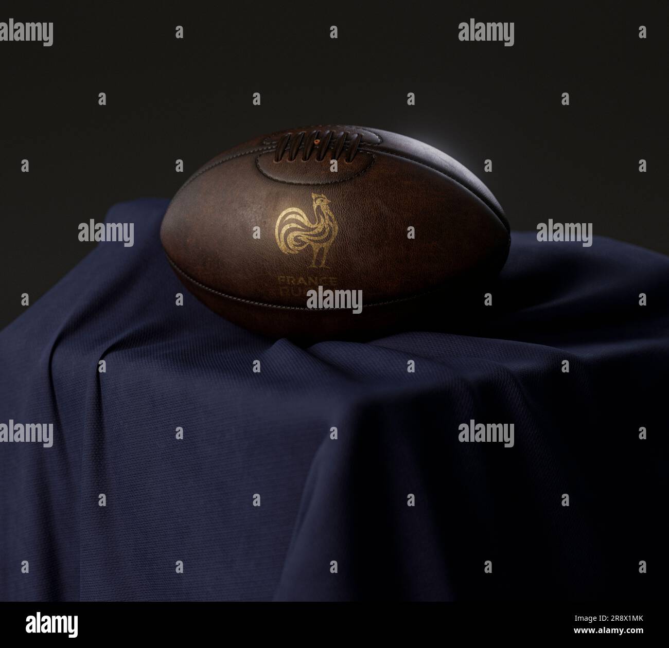 A 3D render of a vintage leather rugby ball with a gold rugby logo resting on a draped navy cloth  - February 13, 2023 in Bristol, United Kingdom Stock Photo