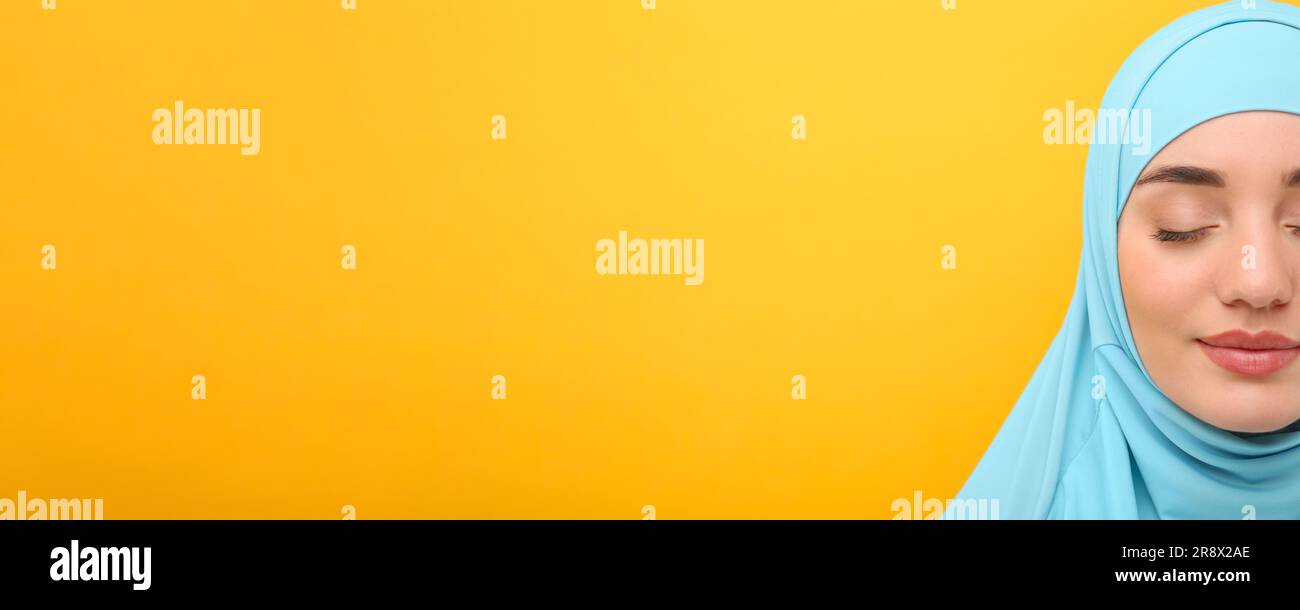 Portrait of Muslim woman in hijab on yellow background, space for text ...