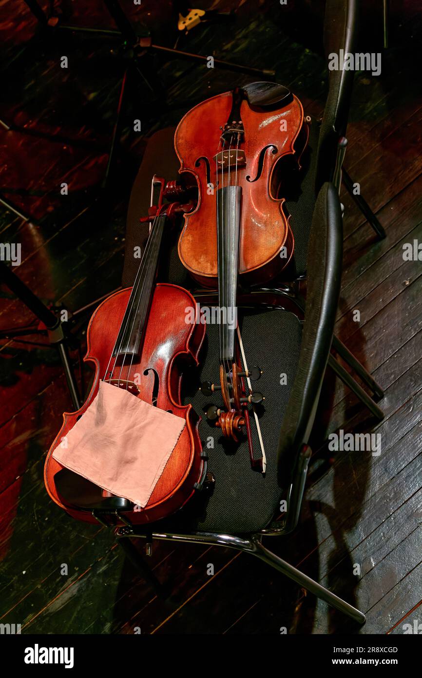 Image two violins of a symphony orchestra lie on chairs during intermission Stock Photo