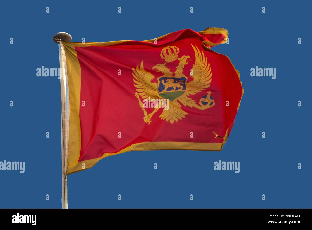 flag-of-montenegro-waving-in-the-wind-with-blue-sky-background-stock