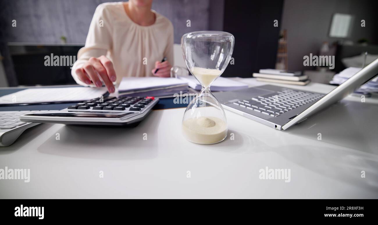 Late Invoice And Billing Deadline With Hourglass At Desk Stock Photo
