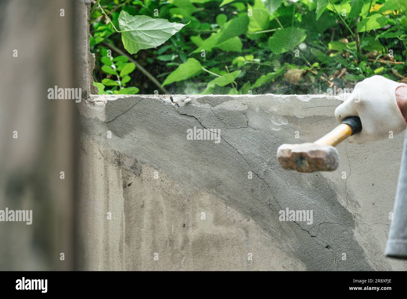 Hand of worker using hammer smashing and demolish on brick block wall