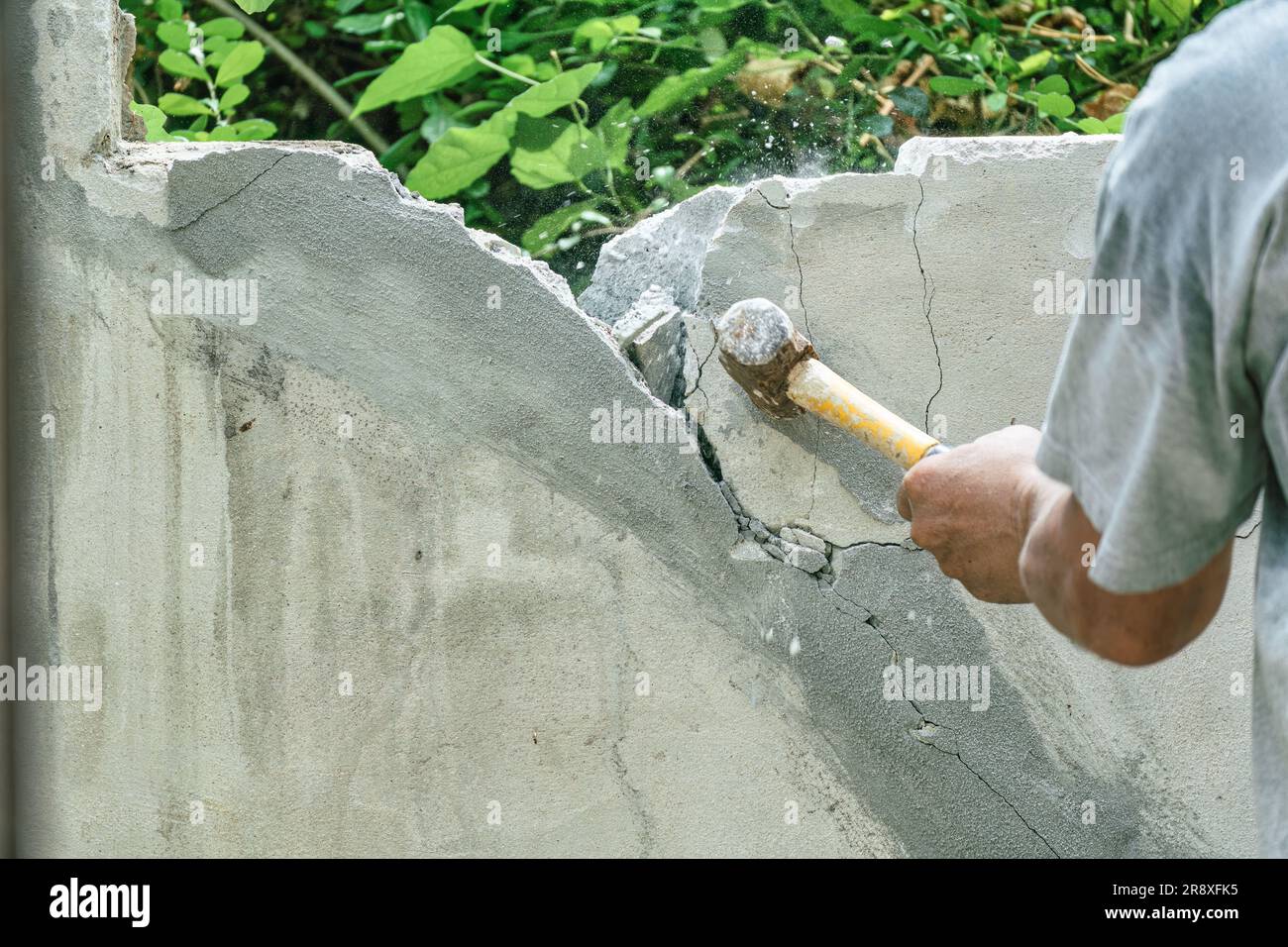 Hand of worker using hammer smashing and demolish on brick block wall