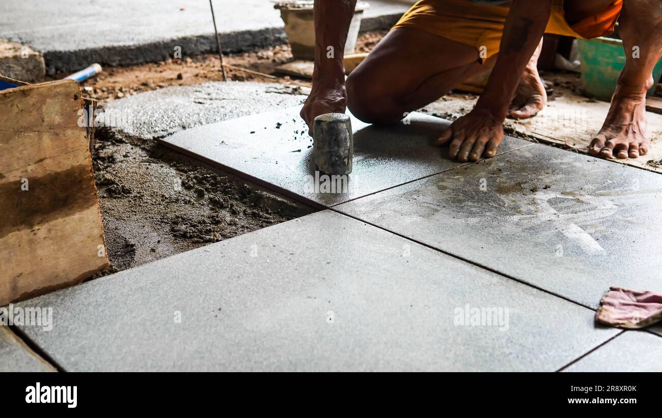A male construction worker installs a large ceramic tile Stock Photo