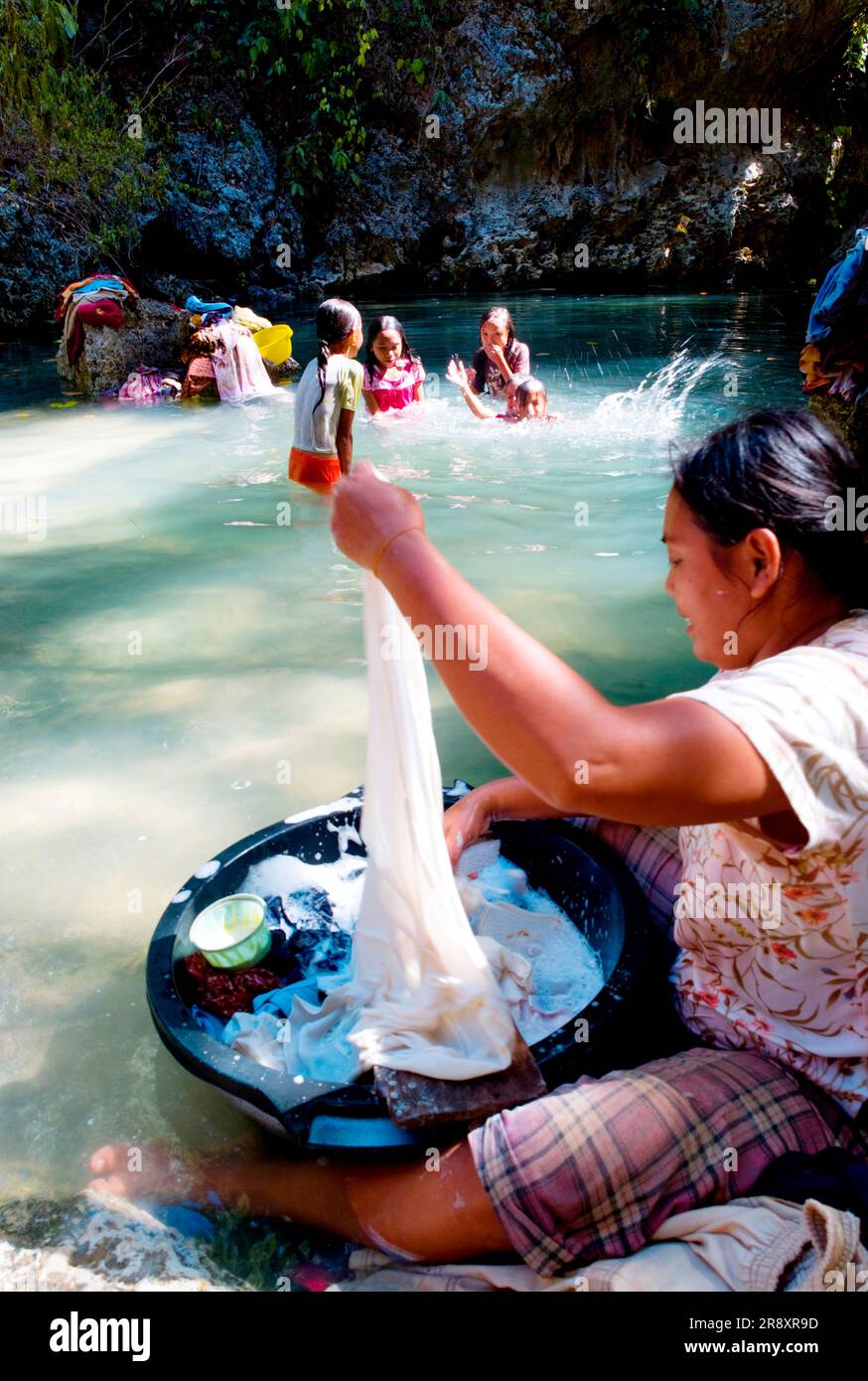 Women wash clothes in the only fresh water available near their village. Stock Photo