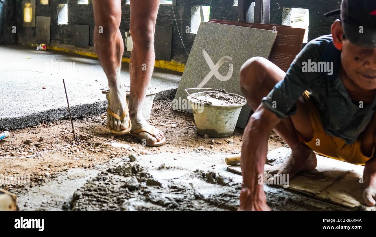 A male construction worker installs a large ceramic tile Stock Photo