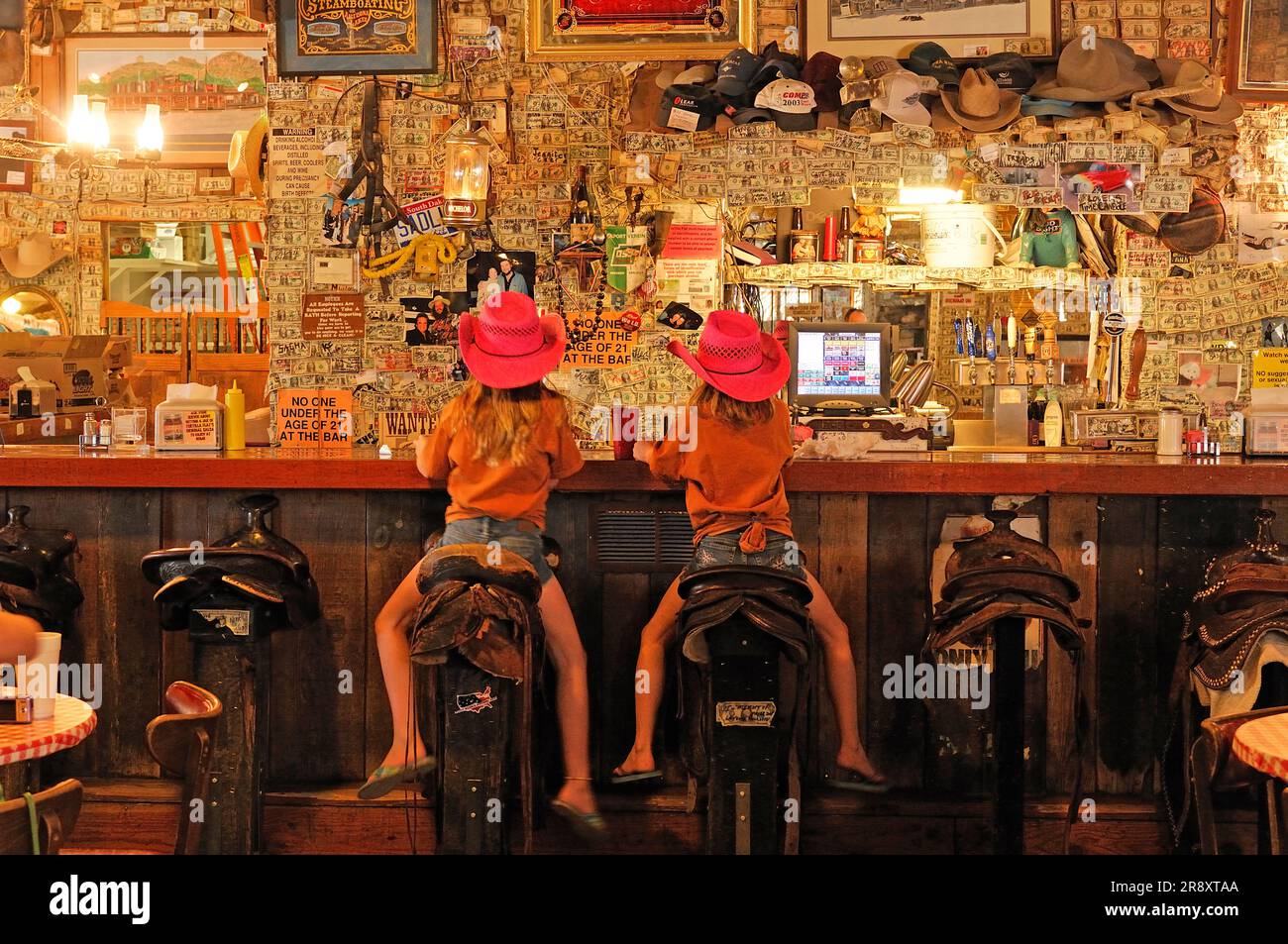 Two girls sitting in saddles at Superstition Saloon Mercantile, Apache Trail, Tortilla Flats, Arizona. Stock Photo