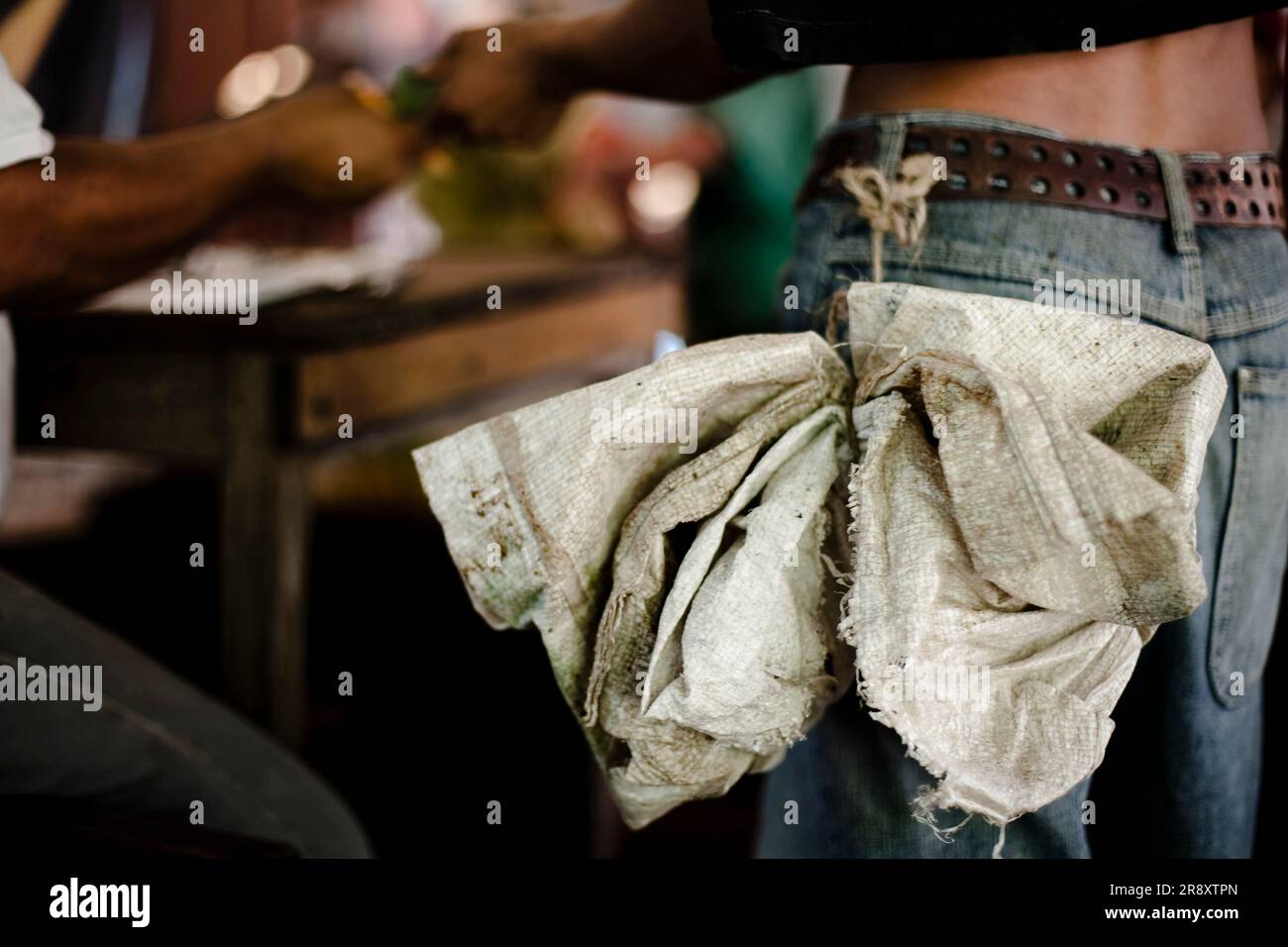 a plastic bag tied to the belt of a man who's getting paid after a day of work at a coffee plant in Chiapas, Mexico. Stock Photo