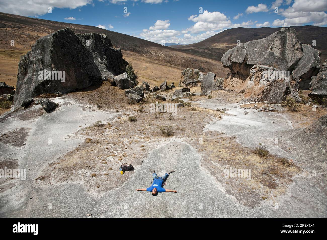 A man lying down between some rocks in Hatun Machay, Peru. Stock Photo