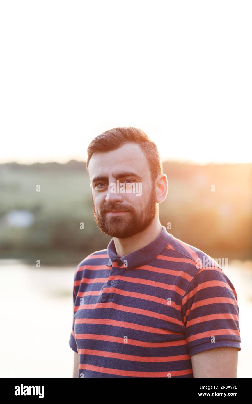 middle-aged man with a beard in a t-shirt in the rays of the sun Stock Photo