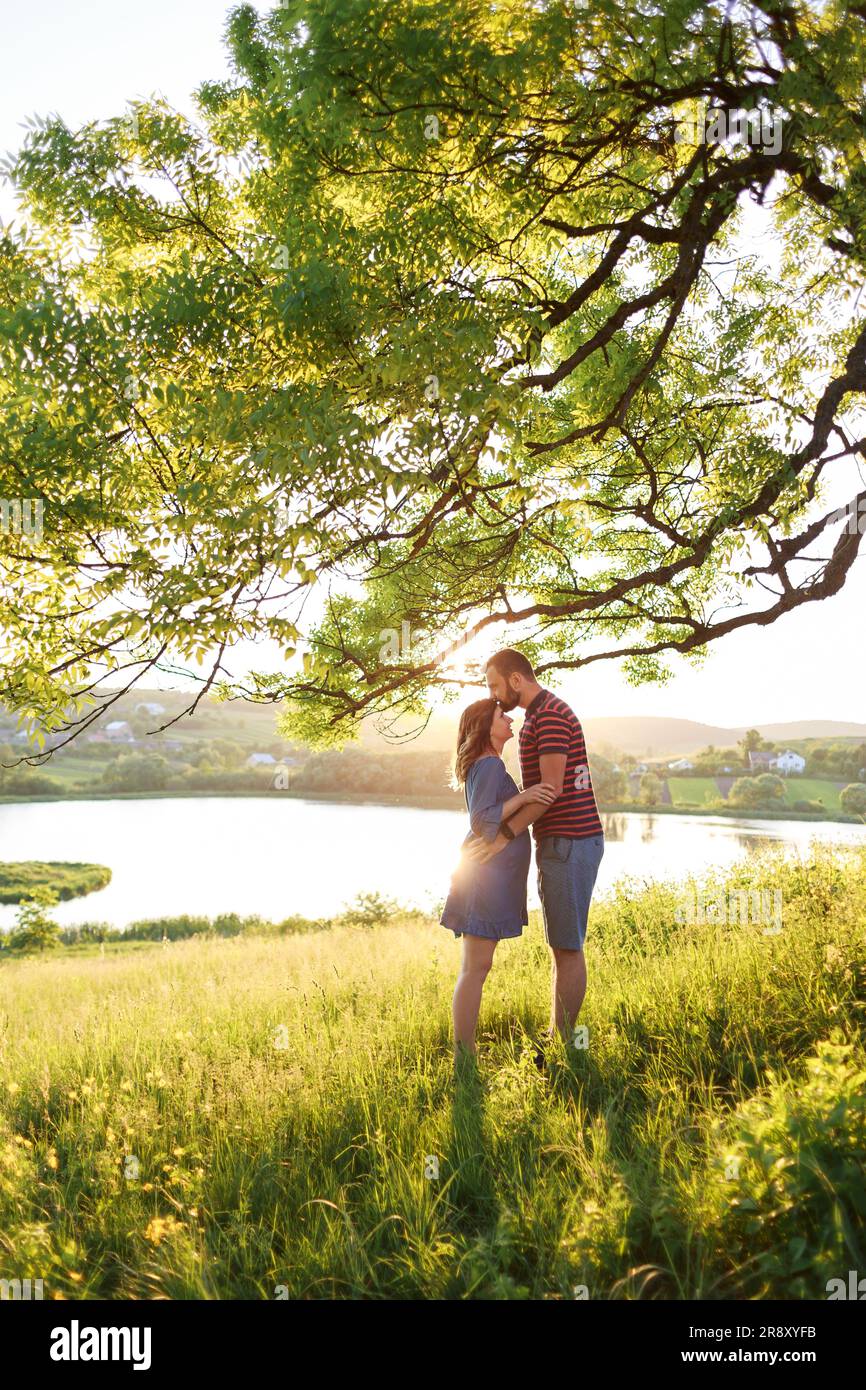 man and woman stand embracing in field of flowers in rays of sun Stock ...