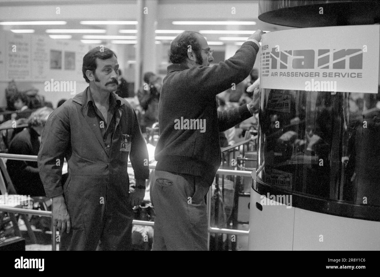 Getting ready, workmen putting up signage while customers ( in background out of focus) waiting through the night for their flight in the morning, Freddie Laker launched Skytrain, the inaugural flight took place amongst much hype on 26th September 1977. This was a no frills low fare, budget daily service between London Gatwick and JFK in New York 1970s UK HOMER SYKES Stock Photo