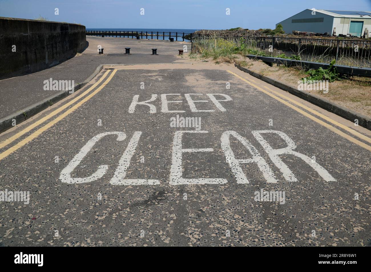 Keep clear painted road markings at a coastal jetty entrance Stock Photo