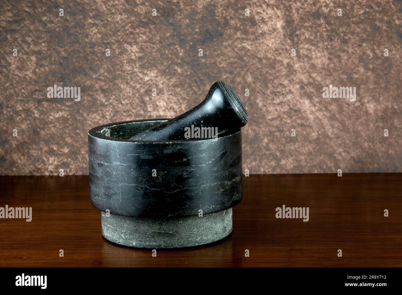 Old stoneware pestle and mortar on a varnished wooden shelf Stock Photo
