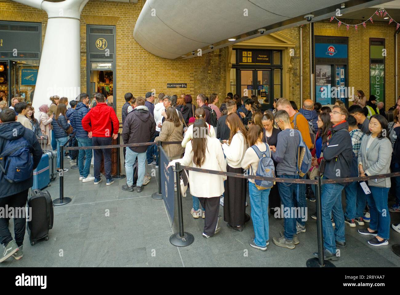 Long queue of people waiting to have their photo taken at Platform 9 3/4 in Kings Cross station Stock Photo