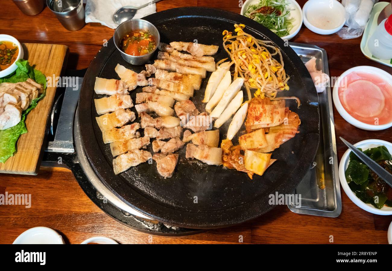 Pan-fried black pork meal in Jeju Korean restaurant, fresh delicious korean food cuisine on iron plate with lettuce, kimchi, banchan and sauce, lifest Stock Photo