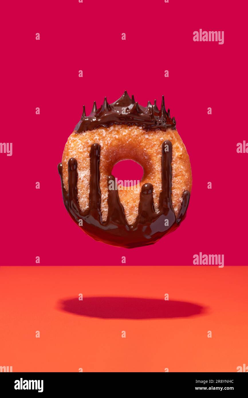 Floating chocolate coated ring doughnut queen concept on vibrant dark