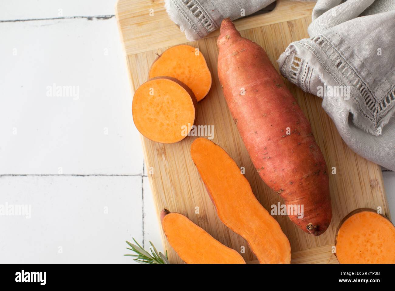 Raw sweet potatoes on cutting board. . Orange kumara, yam. Healthy