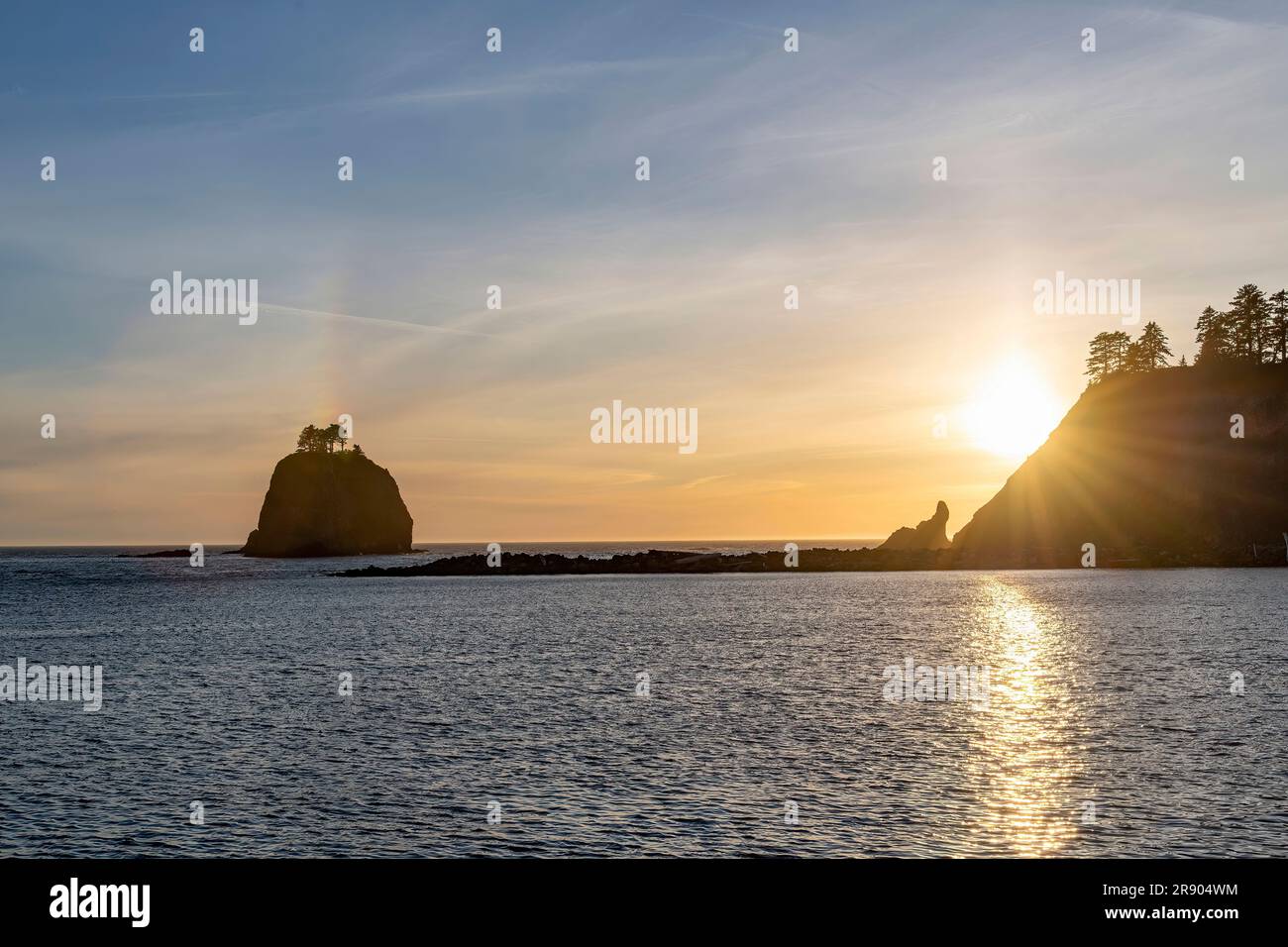 Panoramic sunset view with lens flares of sun rays seen from the coastline of La Push, WA, USA with view on sea stacks near James Island and Little Ja Stock Photo