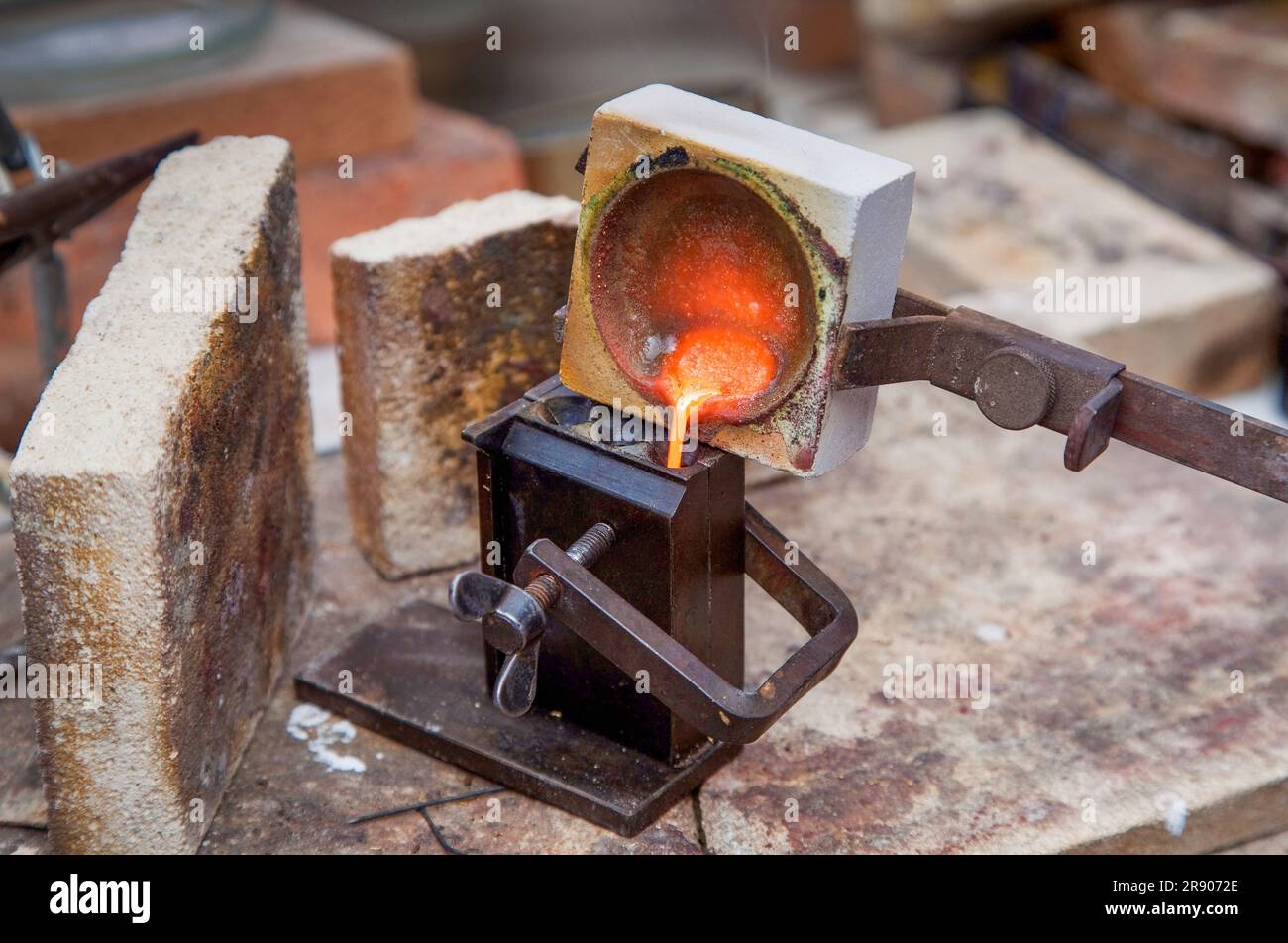 A goldsmith is creating a ring from melted gold. The gold is melted