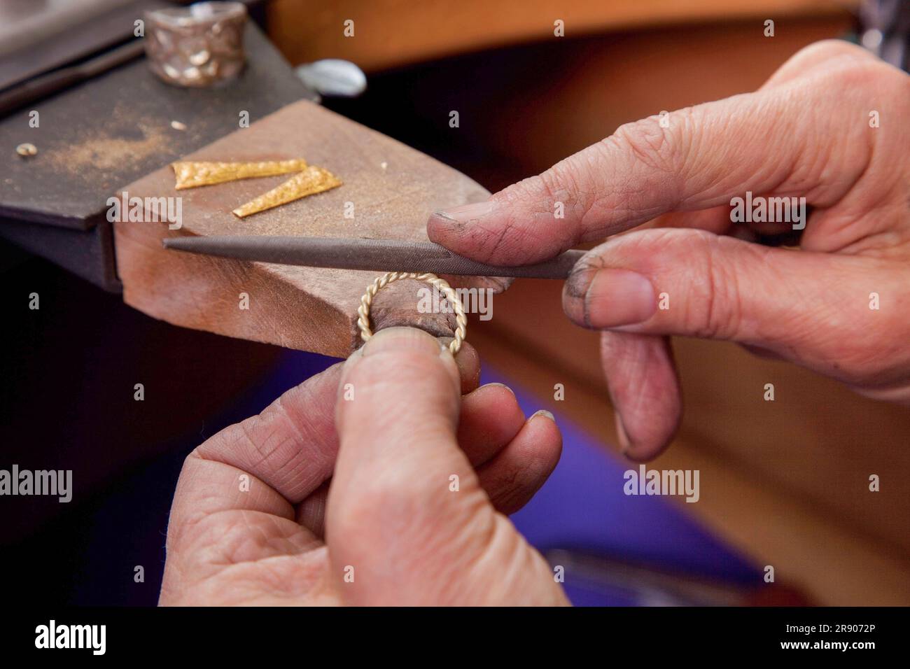 A goldsmith is creating a ring from melted gold. The gold is melted