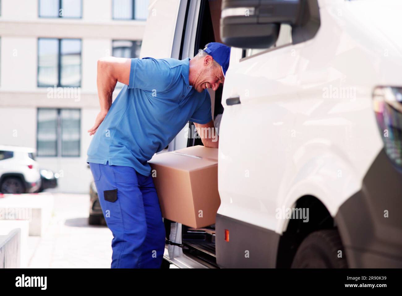 Lifting Box Backpain. Mover With Heavy Boxes Stock Photo